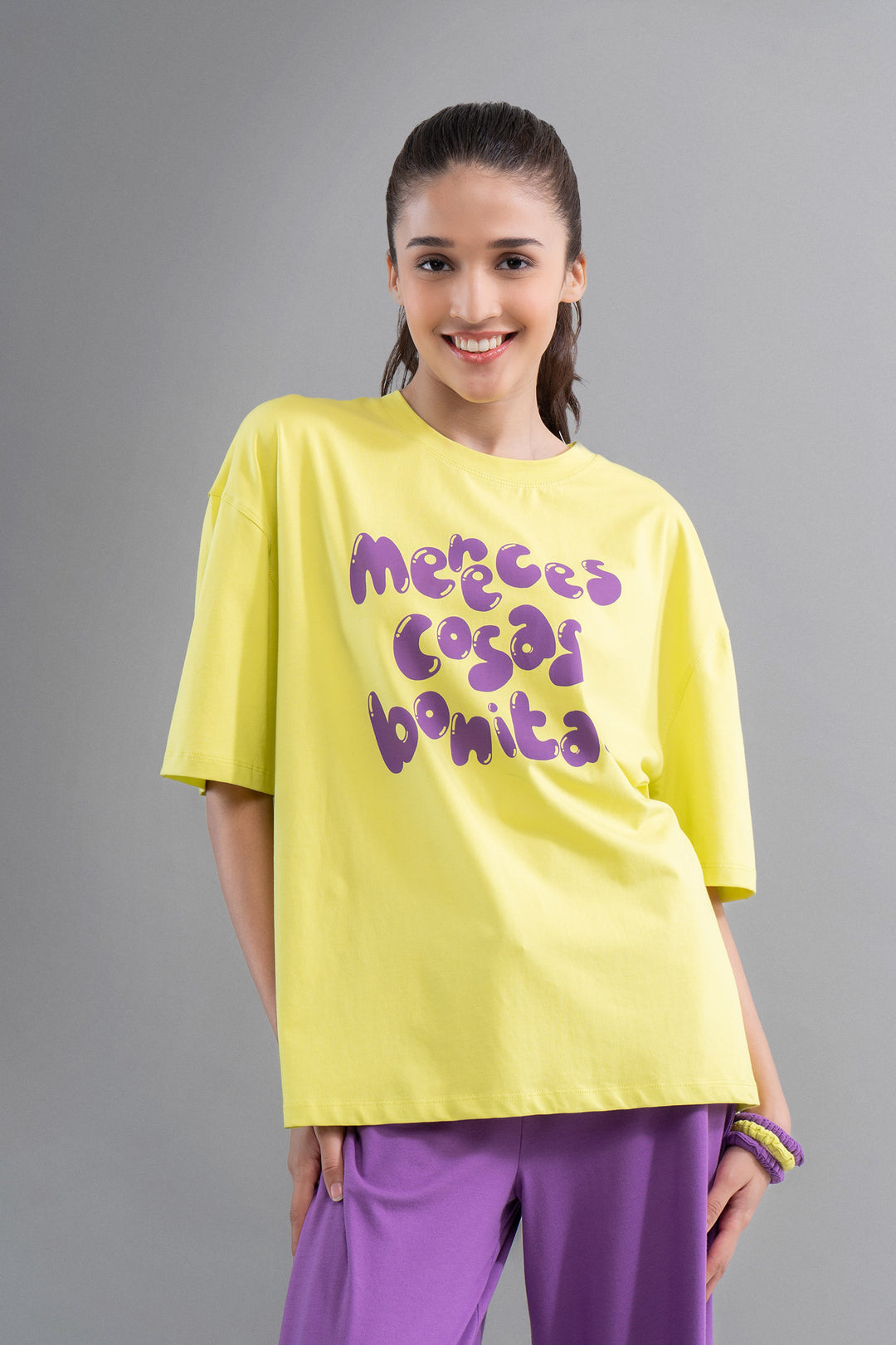 Model wearing a bright yellow oversized top with fun graphic design.