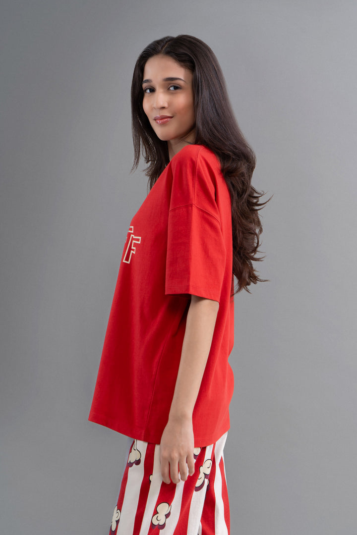 Red oversized t-shirt modeled with stylish pants on gray background.