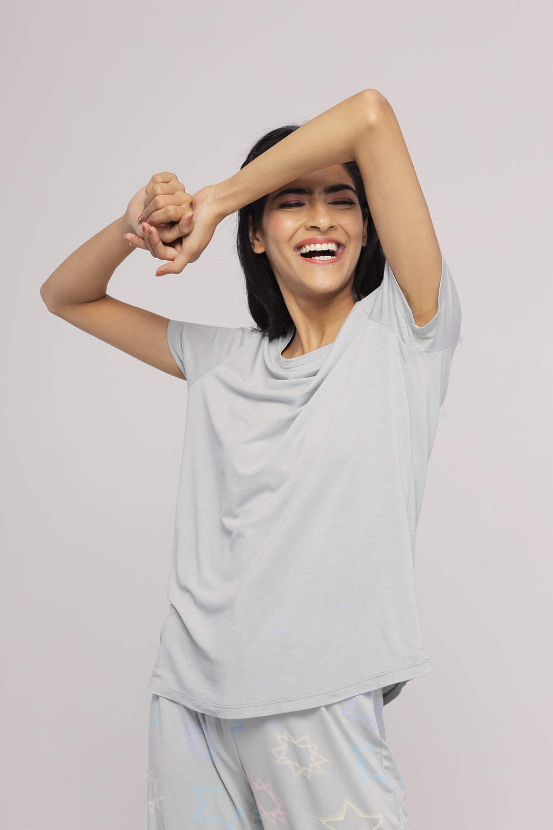 Zen Grey Top modeled by a joyful woman with arms raised.