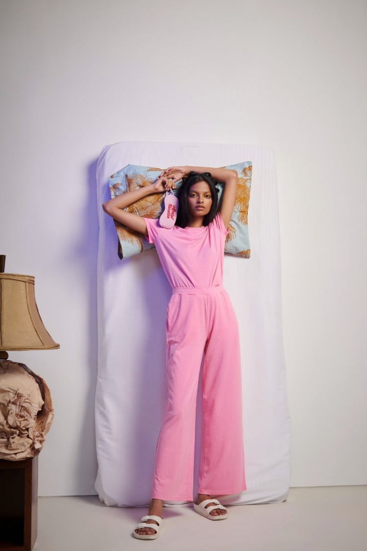 Stylish woman in a pink Supima® co-ord set lounging on a bed.