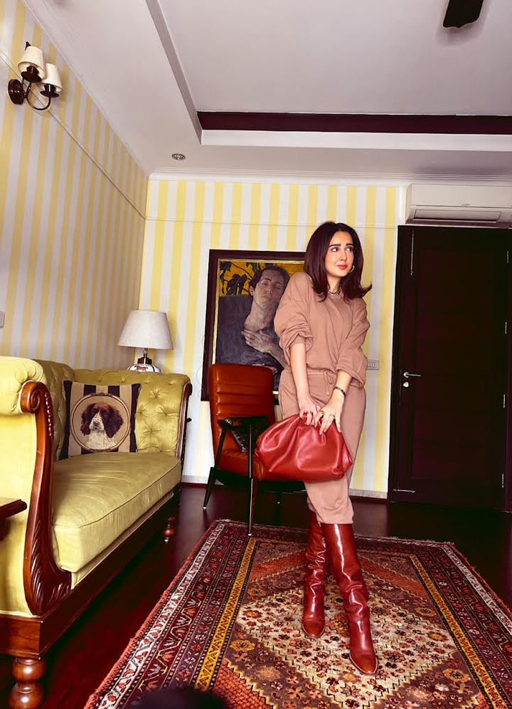 Stylish woman in a brown terry co-ord set holding a red bag.