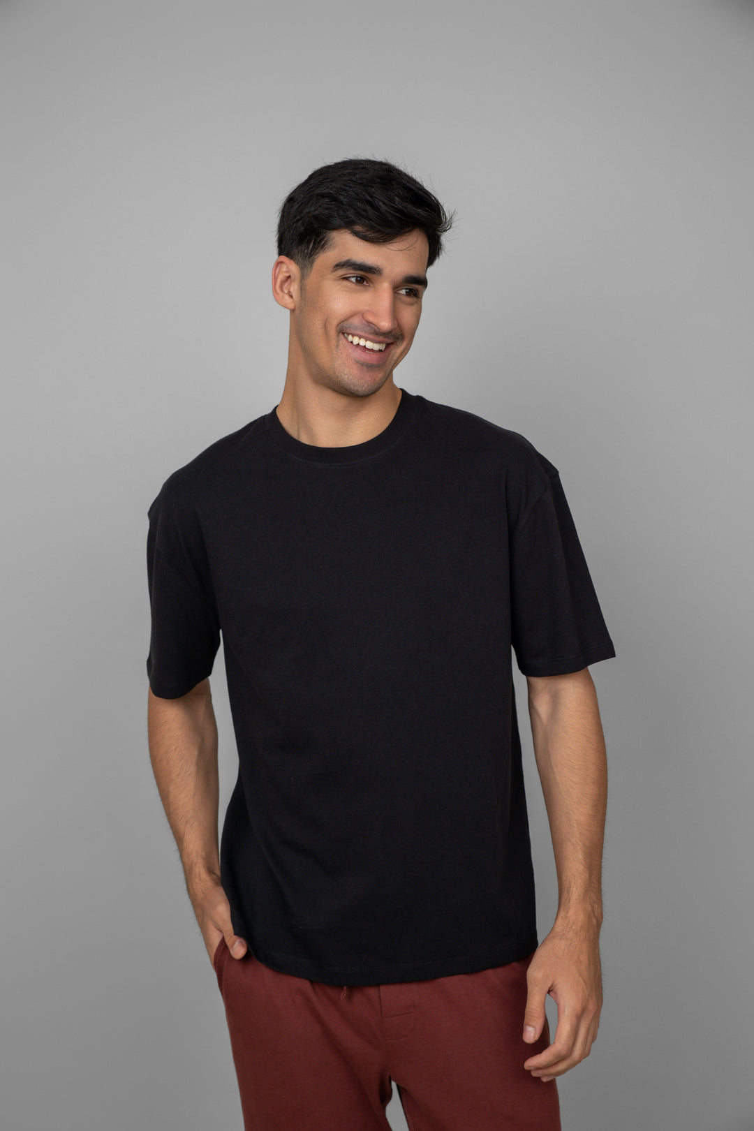 Man smiling in black t-shirt and rust lounge pants.