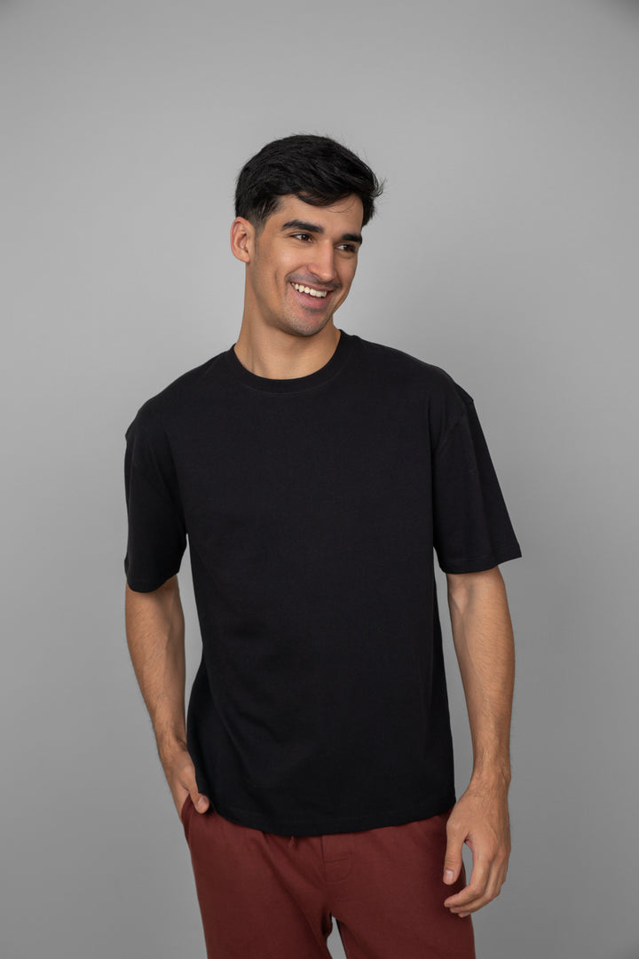 Man smiling in black t-shirt and rust lounge pants.