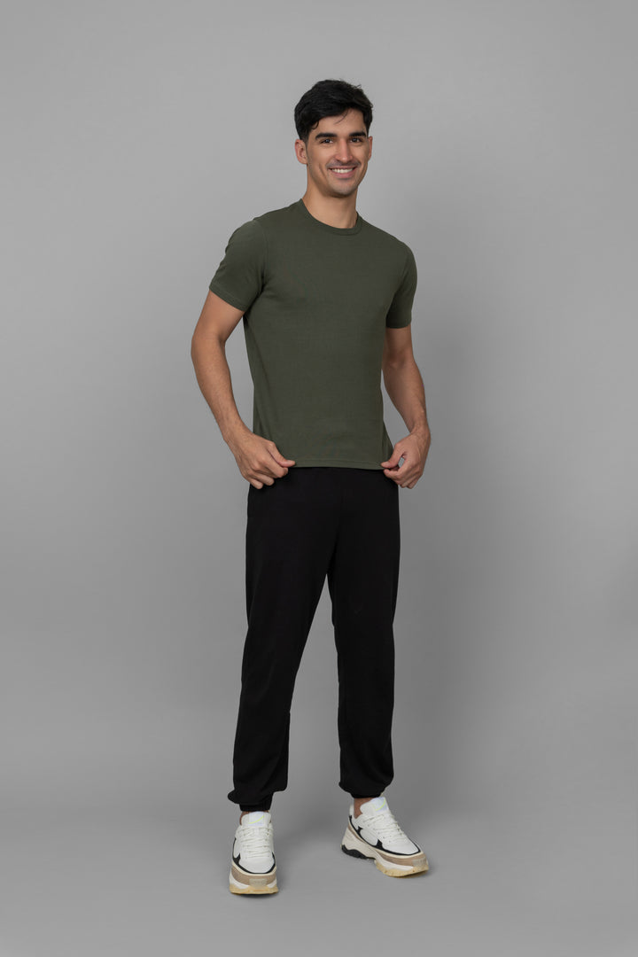 Black men's joggers model wearing a green shirt and stylish sneakers.