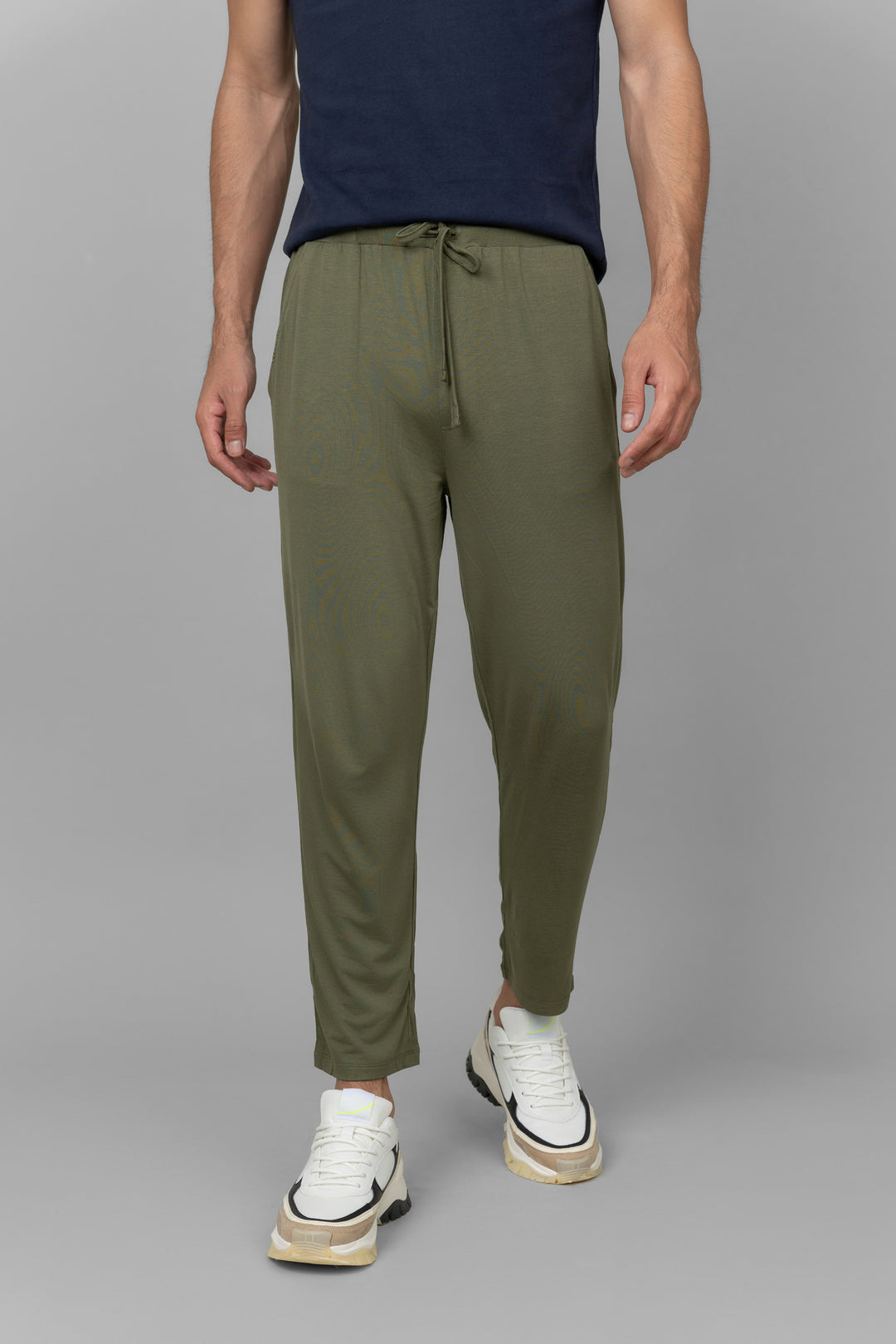 Green men's joggers styled with a navy top and white sneakers.