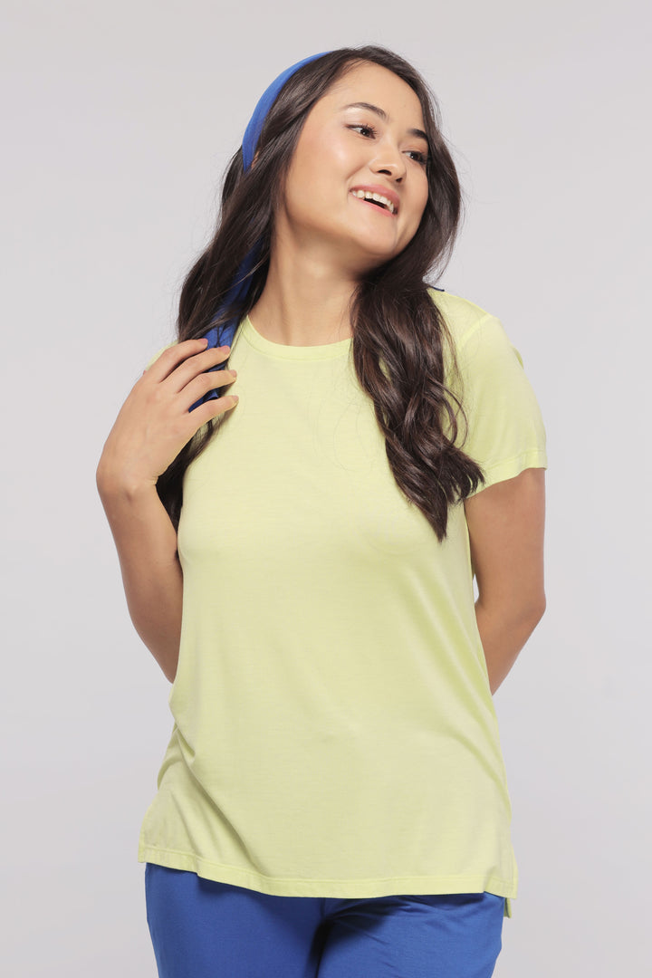 Young woman smiling in a light yellow lounge set outfit.