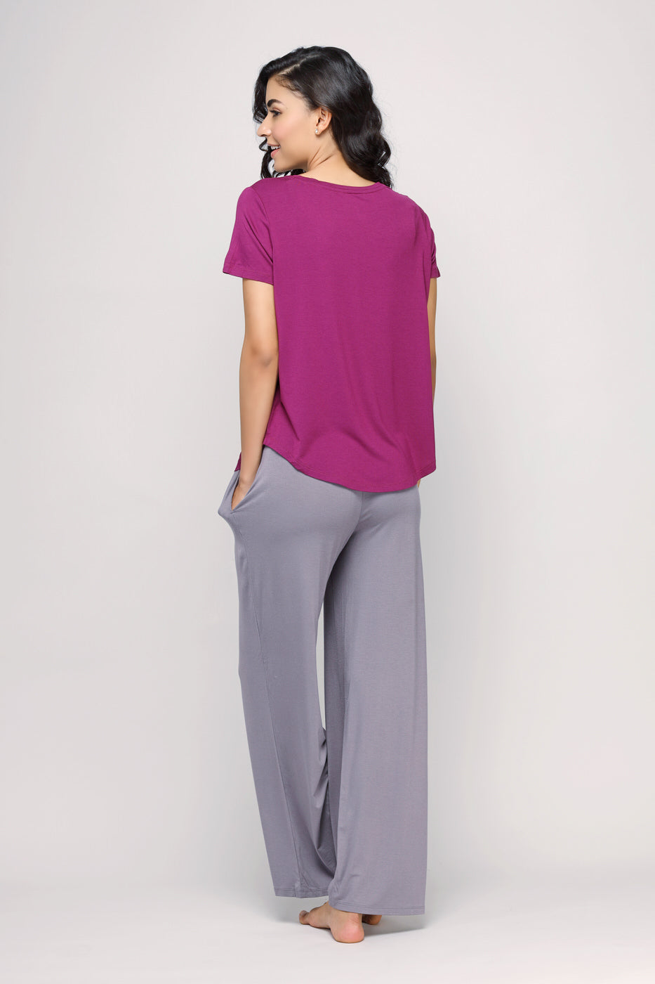 Model wearing Wineberry Top with gray wide-leg pants, back view.