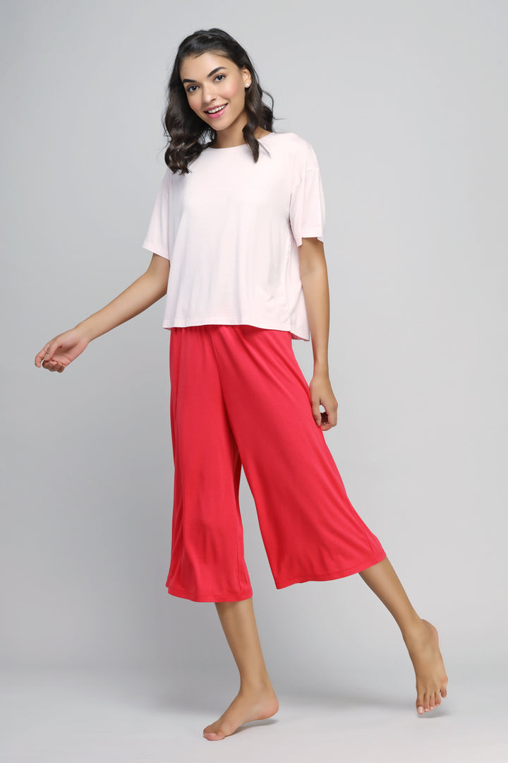 Happy woman wearing a pink top and red culottes set.