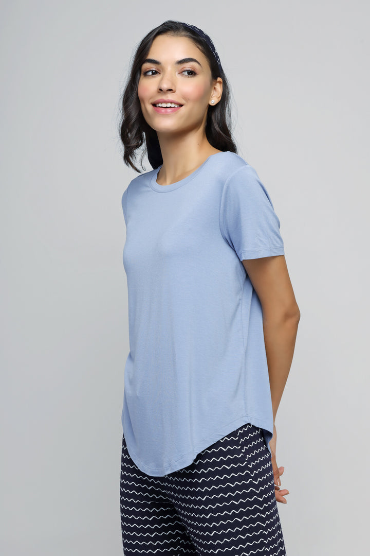 Calming blue pajama set model wearing stylish short-sleeve top and patterned pants.