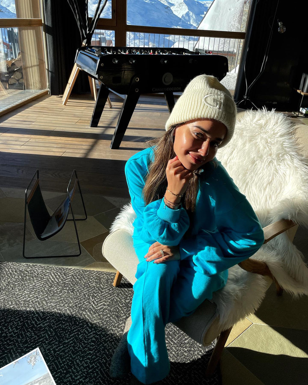 Woman in turquoise Aqua Terry Travel Loungers, cozy indoor setting with mountains.