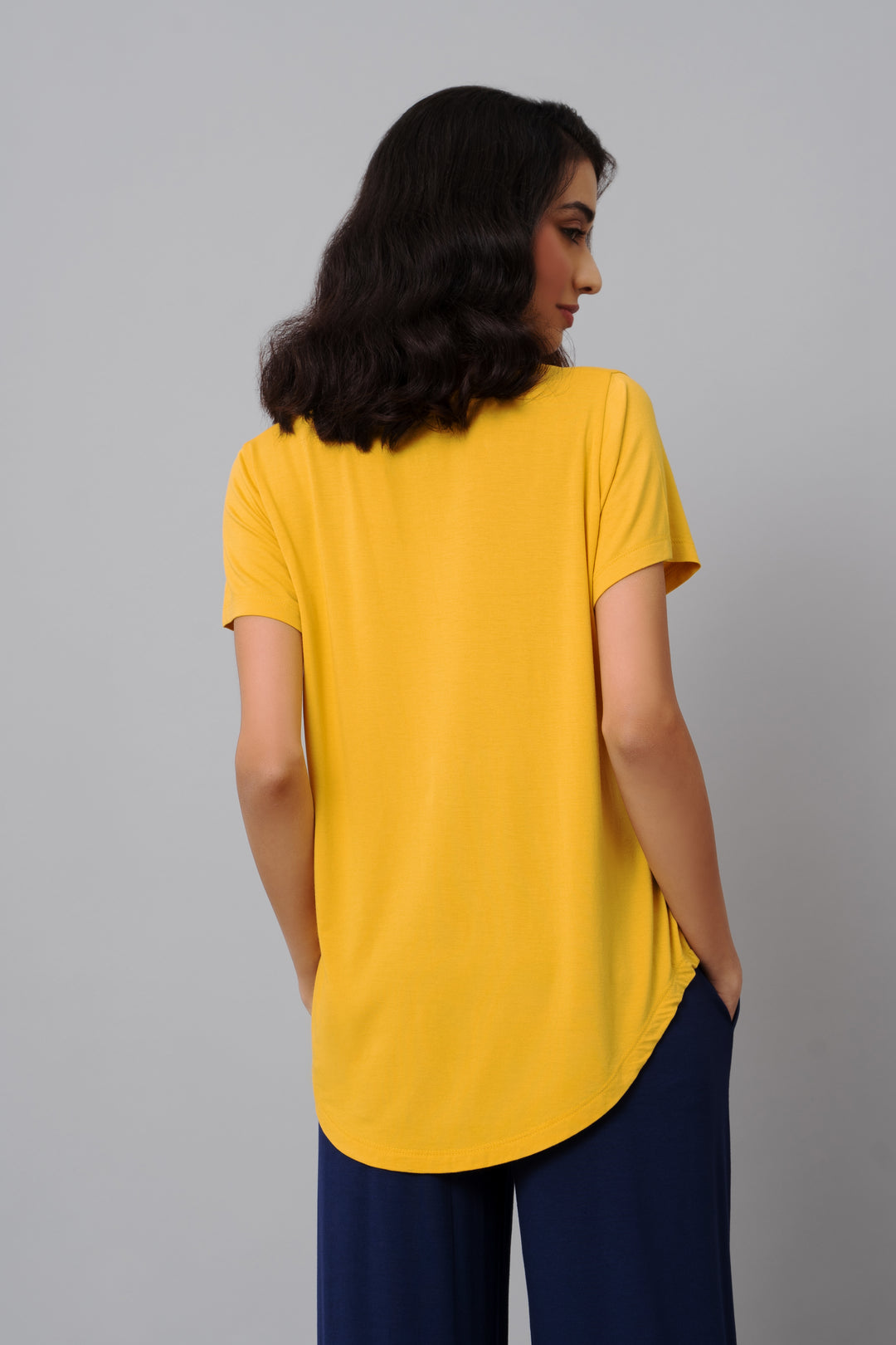 Buttercup yellow top styled with navy pants, back view.