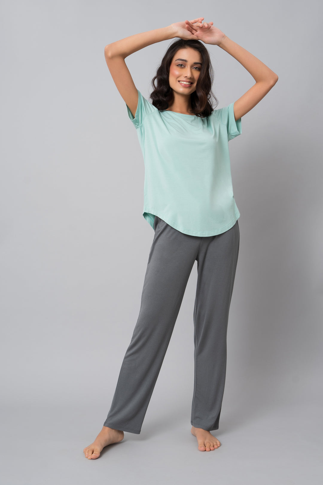 Woman smiling in grey pearl straight lounge pants and mint top.