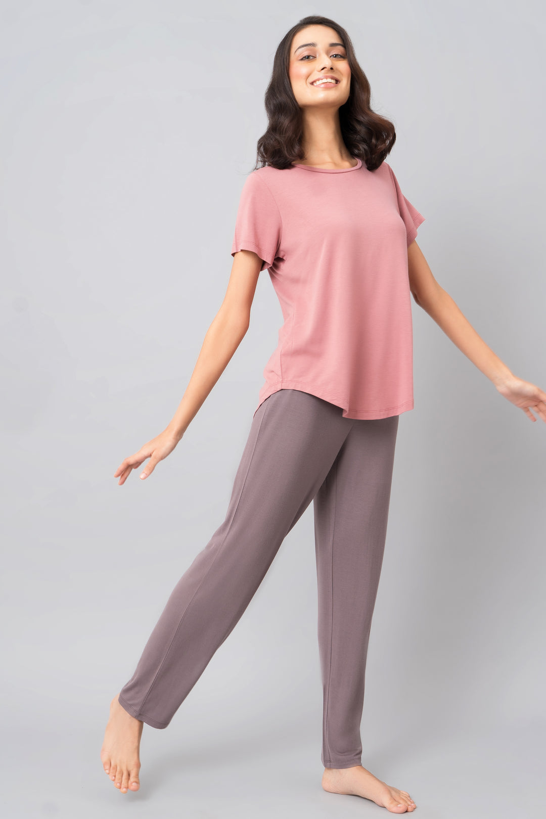 Woman smiling in pink top and grey lounge pants, showcasing Sweet Oak Straight Lounge Set.