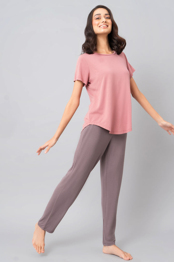 Woman smiling in pink top and grey lounge pants, showcasing Sweet Oak Straight Lounge Set.