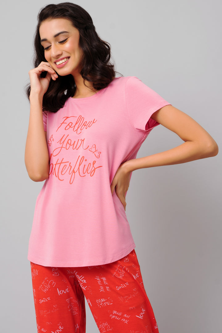 Model wearing pink "Follow Your Butterflies" top with stylish red pants.