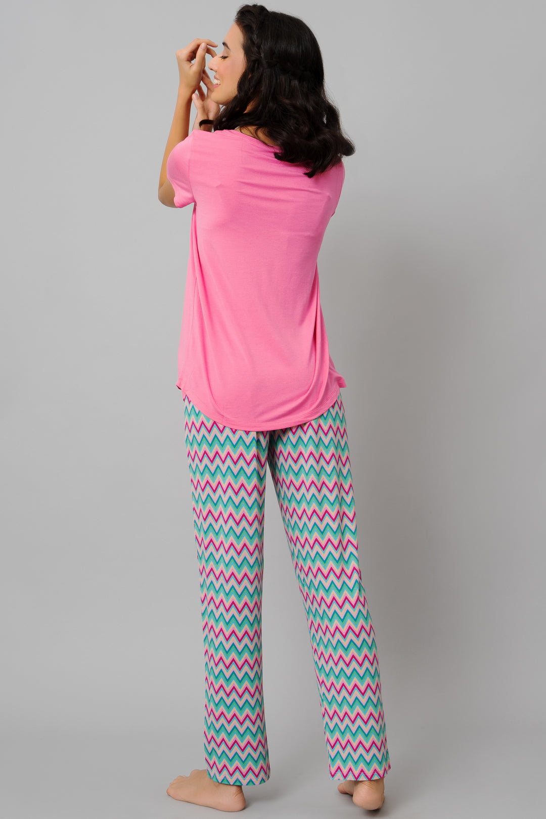 Model wearing a mellow pink top and patterned pajama pants.