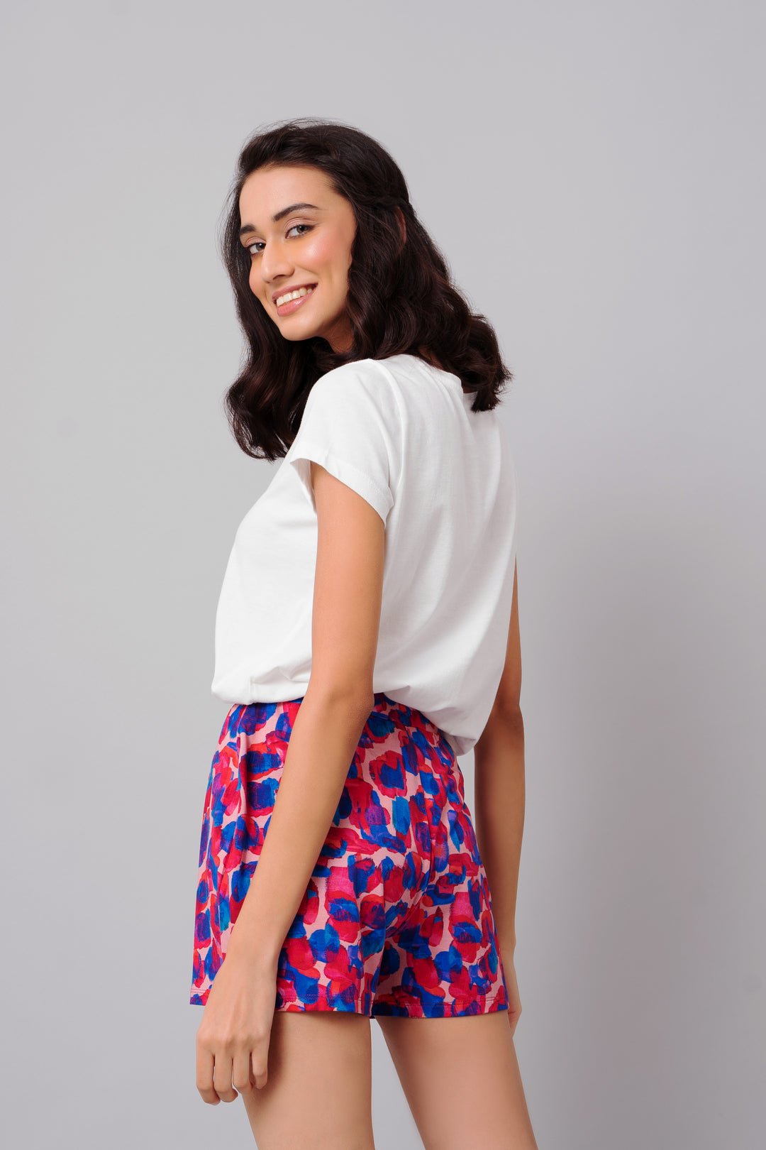 Artsy watercolor shorts on model with white top, colorful design.