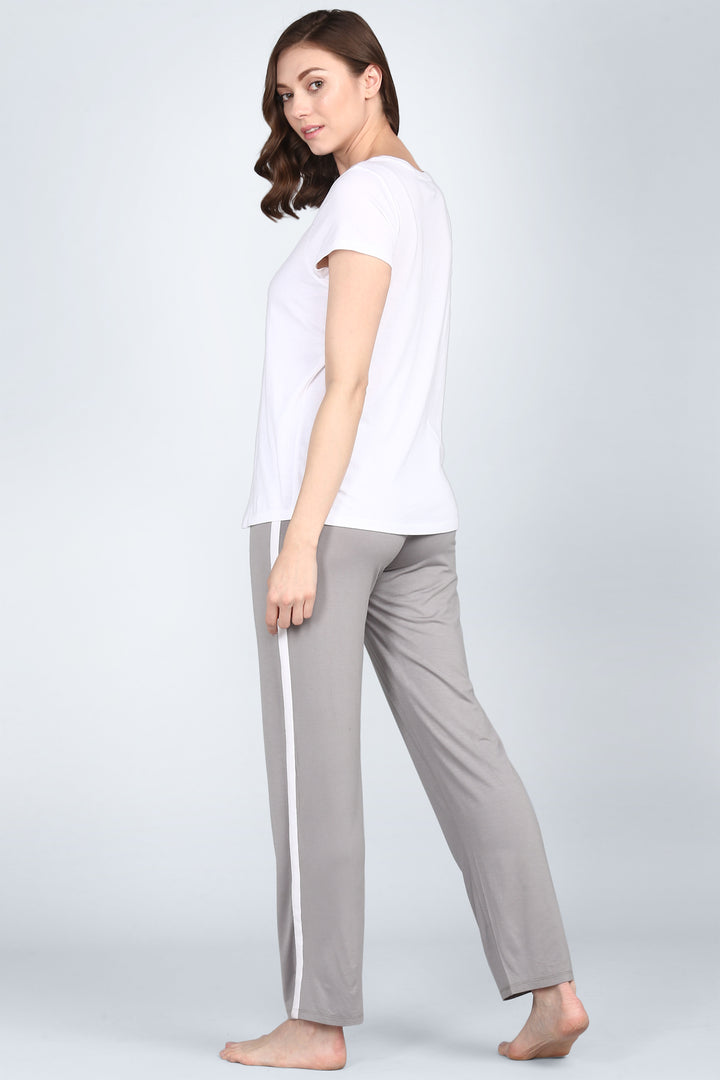 Woman in deep grey pajama set with white accents, side view.