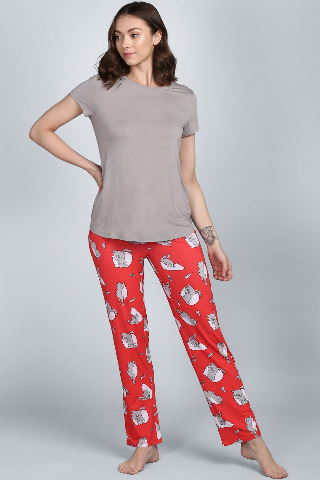 Woman wearing Lazy Cat Pajamas with playful cat designs on red pants.