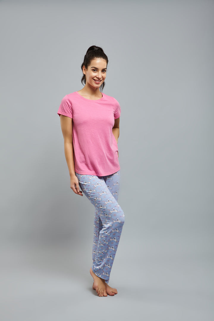 Woman wearing Loveable Rabbit Pajamas, featuring pink top and patterned pants.