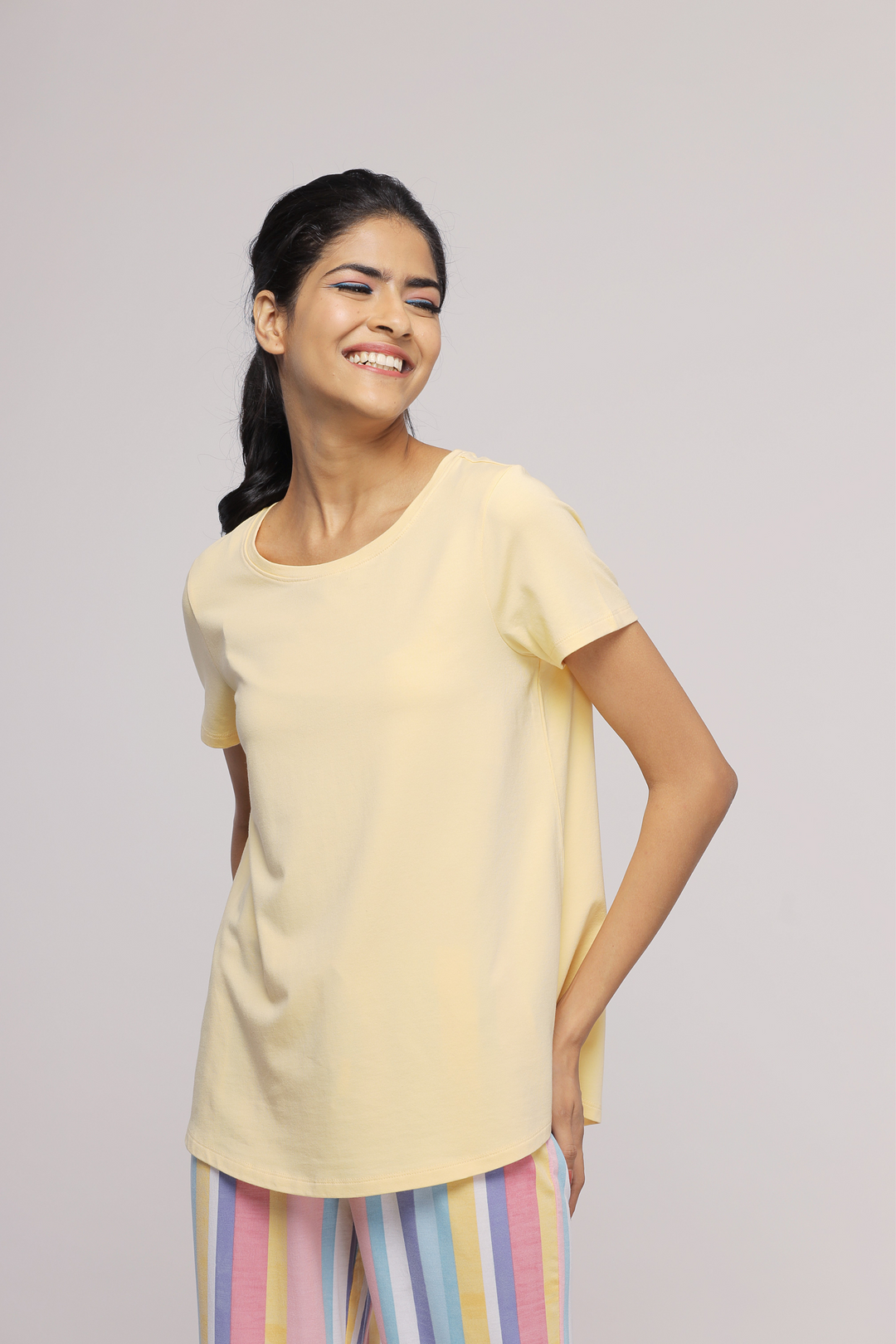 Model wearing Soft Summer Pajama Set with yellow top and striped pants.