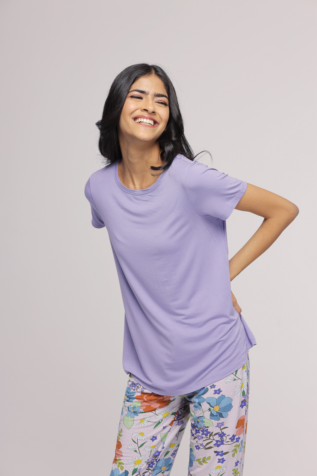 Smiling model wearing the Sweet Orchid Top with floral pants.