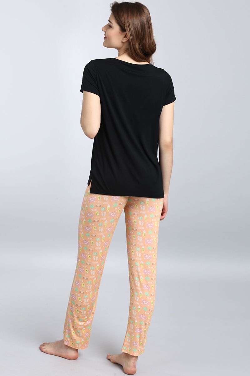 Woman wearing Dreamy Weekend Pajama Set, featuring a black top and patterned pants.